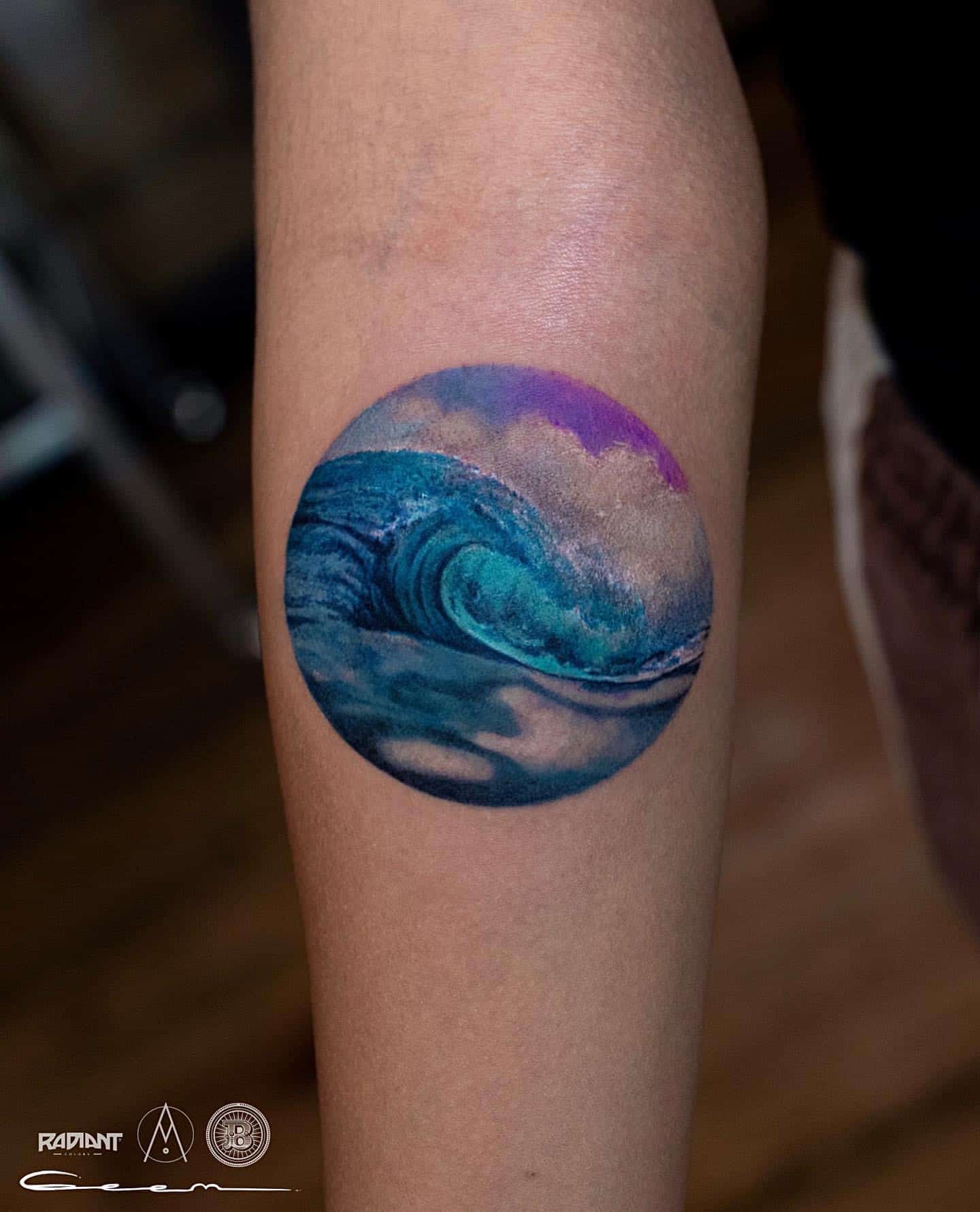 Origami boat on a watercolor wave tattoo on the left